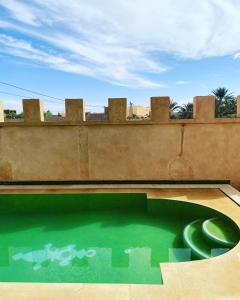 a swimming pool with a green object in front of a wall at Desert Villa Boutique Hotel Merzouga in Merzouga