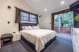 a bedroom with a bed and a large window at Maison Blanc Lodge in Auckland
