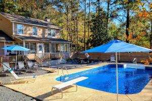 a swimming pool with a blue umbrella and a house at Lakefront Macon Home with Pool, Dock and Fire Pit! in Macon