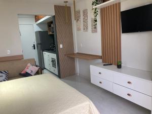 a bedroom with a bed and a dresser with a television at Flat frente mar na Praia do Pero com piscina in Cabo Frio