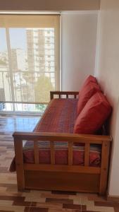 1 cama con almohadas rojas en una habitación con ventana en Hermoso 2 ambientes en Palermo Hollywood en Buenos Aires