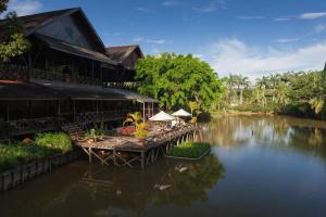 a building with tables and chairs on a river at Sepilok Nature Lodge - Formerly known as Sepilok Nature Resort in Sandakan