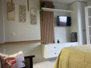 a bedroom with a bed and a dresser and a tv at Flat frente mar na Praia do Pero com piscina in Cabo Frio