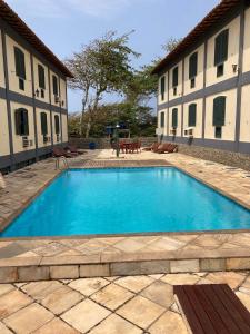 a large blue swimming pool in front of two buildings at Flat frente mar na Praia do Pero com piscina in Cabo Frio