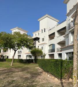 a white building with a tree in front of it at Apartment in Hacienda Riquelme Golf Resort in Sucina
