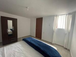 ein Schlafzimmer mit einem Bett mit einer blauen Decke darauf in der Unterkunft Exclusivo Apartamento en el Centro Histórico Trujillo - 3er Piso in Trujillo