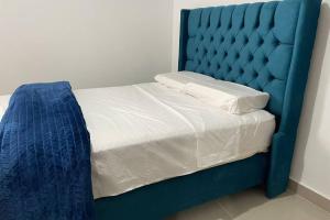 Exclusivo Apartamento en el Centro Histórico Trujillo - 3er Piso في تروخيو: سرير مع اللوح الأمامي الأزرق والشراشف البيضاء