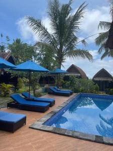 a swimming pool with blue umbrellas and a resort at Kelingking Tatakan Bungalow in Nusa Penida