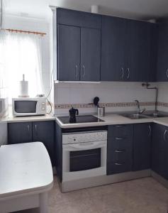 una cocina con armarios azules y un horno de fogón blanco en Apartamento Las Brisas, en Rincón de la Victoria