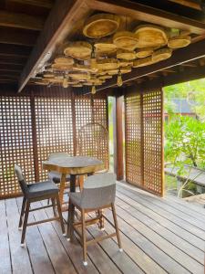 uma mesa e cadeiras de madeira num deque de madeira em The Temak Villa em Pantai Cenang