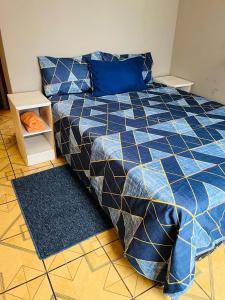a bed with a blue and black comforter in a room at Izinjiki Namacusi Guest House in Amsterdam