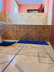 a bathroom with a toilet and a tiled floor at Izinjiki Namacusi Guest House in Amsterdam