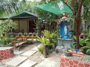 a garden in front of a house with a bench at Ennas Place in Coron