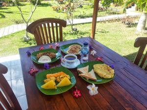 a wooden table with plates of food on it at Dekara Cottages in Nusa Penida