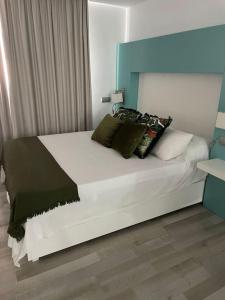 a bedroom with a large white bed with black pillows at Playa del Pirata IKiGai in San Bartolomé