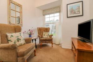 a living room with a flat screen tv and chairs at Eden House Wing in Saint Keverne