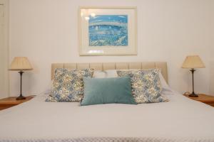 a bedroom with a white bed with pillows and two lamps at Eden House Wing in Saint Keverne