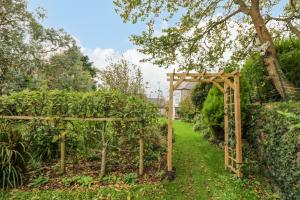 un arco de madera en un jardín con un camino en Eden House Wing, en Saint Keverne