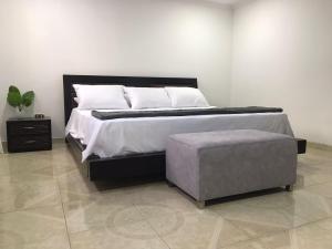 a bedroom with a large bed and a ottoman at Aloja-T en zona centrica de Armenia in Armenia