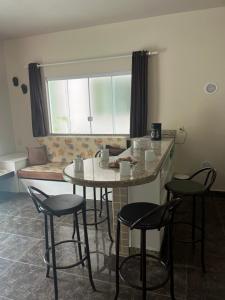 a kitchen with a table and stools in a room at La Lola Residencial in Bombinhas