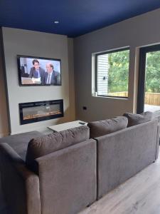 a living room with a couch and a tv on the wall at Lough View Lodge in Dunnamanagh