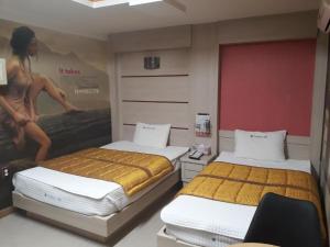 a room with two beds and a poster on the wall at Diamond Motel in Sacheon