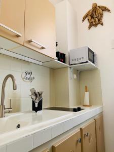uma cozinha com um lavatório e um micro-ondas em SWILODGE VUE SUR MER ! Petit Déjeuner et Location de voiture possible em Le Moule