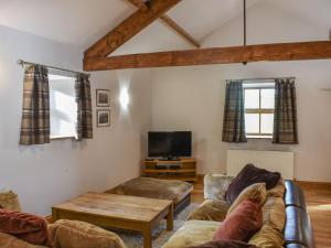 a living room with a couch and a tv at Uk39799 - Old Corner Barn in Troutbeck
