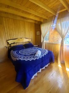 1 dormitorio con 1 cama azul en una casa de madera en Acogedora pieza privada en casa frente al mar y al parque el Pudu, en San Antonio de Chadmo