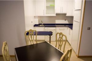 una cocina con mesa negra y sillas. en Apartamentos Turisticos Noray, en Argoños