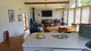 eine Küche und ein Wohnzimmer mit einem Tisch und einer Obstschale in der Unterkunft Quiet cul de sac, close to Abel Tasman in Motueka
