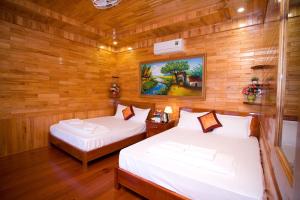 2 camas en una habitación con paredes de madera en Phong Nha Tuan Garden House, en Phong Nha