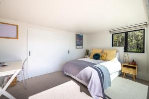 a bedroom with a bed and a desk and a window at Moana Retreat in Putaki Bay
