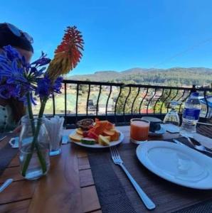 einen Tisch mit einem Teller Essen und Blumen darauf in der Unterkunft THE EDGWARE in Nuwara Eliya