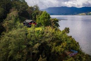 帕斯托的住宿－Cabaña Colibri naturaleza vista Laguna de la Cocha，水体旁山丘上的房屋