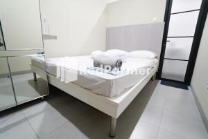 Una cama de hospital con sábanas blancas y almohadas. en Tomang Gelong Guest House Syariah Mitra RedDoorz en Yakarta