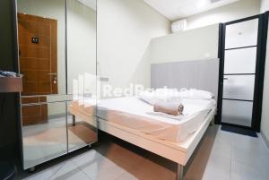 1 dormitorio con 1 cama y pared de cristal en Tomang Gelong Guest House Syariah Mitra RedDoorz en Yakarta