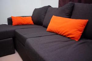 a black couch with two orange pillows on it at Aladdín Departamentos in Ciudad Lujan de Cuyo