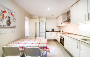a kitchen with white cabinets and a table and chairs at 2 Bedroom Amazing Apartment In Casares in Casares