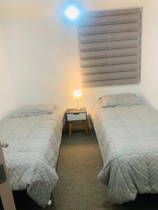 um quarto com duas camas e uma mesa com um candeeiro em SENSACIONAL DEPTO em Antofagasta