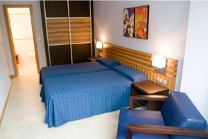 a bedroom with a blue bed and a couch at Apartamentos Turisticos Noray in Argoños