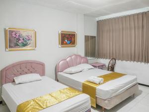 a bedroom with two beds and a window at Yellow Sapphire RedPartner near Mayjend Sungkono in Surabaya