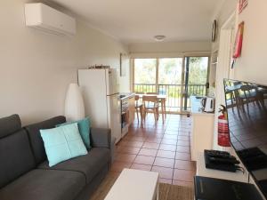 a living room with a couch and a kitchen at Grandeur Holiday Units in Merimbula