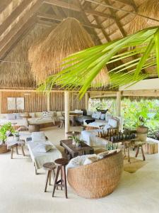 布桑加的住宿－The Beach House Ocam Ocam，一个带沙发和桌子的度假村大堂和稻草屋顶