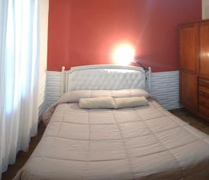 1 cama en un dormitorio con una pared roja en Casa alojamiento Sweet IZABEL Con pileta y estacionamiento privado! en Chascomús