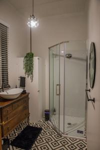Owhango的住宿－5-Star OLD POST OFFICE HOLIDAY HOME - 5-7-Bedroom Art Deco Elegance，一间带玻璃淋浴和水槽的浴室