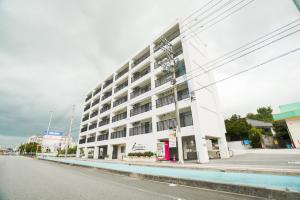 un grand bâtiment blanc sur le côté d'une rue dans l'établissement HOTEL HOUKLEA, à Nago