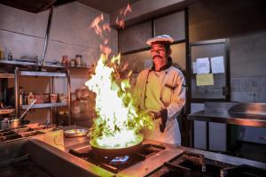a chef standing in a kitchen with a pot on a stove at Bharatpur Garden Resort in Bharatpur +37 photos