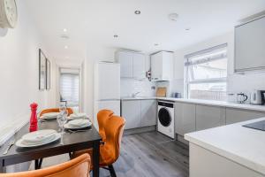 a kitchen with a table and chairs in a kitchen at Dainty 2BD Flat in Greater London in London
