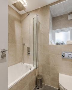 a bathroom with a shower and a tub and a toilet at Dainty 2BD Flat in Greater London in London